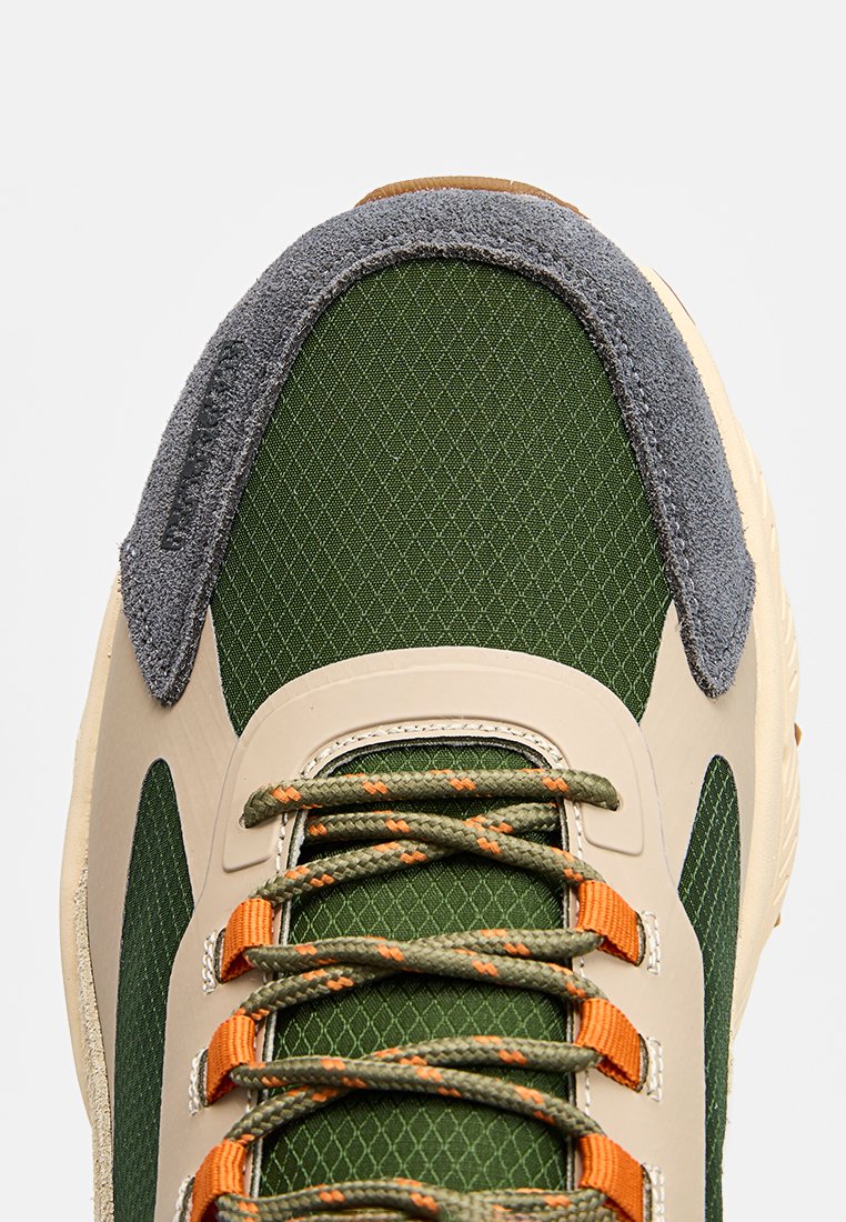 Zapatillas de malla verde con acentos de ante gris, detalles en beige, cordones naranjas y un diseño texturizado. Presenta una puntera redondeada y suela acolchada.