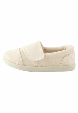 Beige kankaan liukuva kenkä, jossa on pyöreä kärki, tarranauha ja kumipohja. Kenkässä on teksturoitu kangasmateriaali ja hillitty ompelusyys.