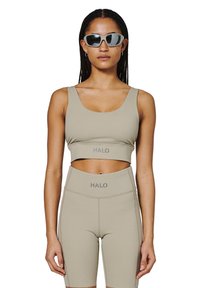 Beżowy zestaw sportowego biustonosza i spodenek o wysokiej talii z logo "HALO". Gładki, elastyczny materiał, dopasowany krój i skrócona sylwetka.