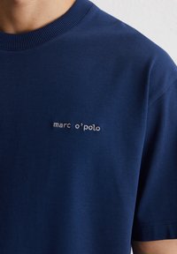 Navyblauwe katoenen t-shirt met een geribbelde ronde hals en korte mouwen, met een discreet wit geborduurd merklogo op de borst.