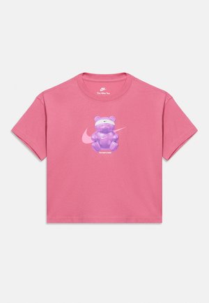 Różowy krótki top z krótkim rękawem z fioletowym gumowym misiem noszącym białą opaskę na głowę, logo Nike z tyłu i tekst „the beary best” z przodu.