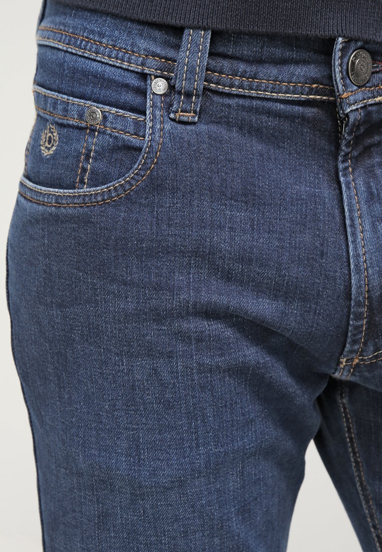 Dunkelblaue Denim-Jeans mit einer glatten Textur, klassischem Fünf-Taschen-Design, kupferfarbener Stickerei und metallischen Hardware-Details.