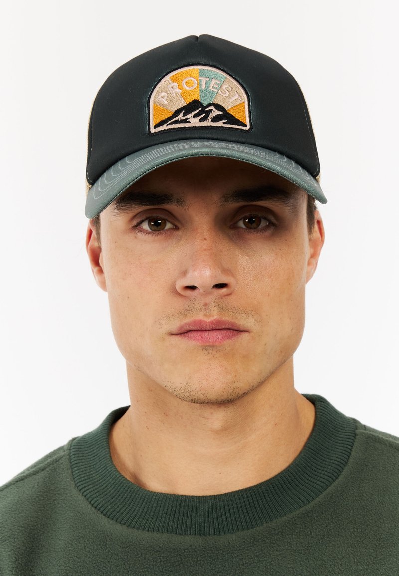 Dark green cap with a curved brim, featuring a multi-colored embroidered patch saying "PROTEST" and mountain design. Cotton blend material.