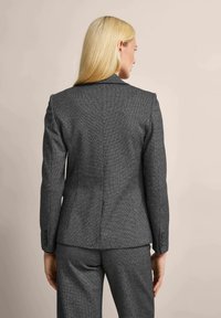 Gray herringbone blazer with a tailored fit, structured shoulders, and buttoned cuffs. Smooth fabric with a subtle texture. Back view.