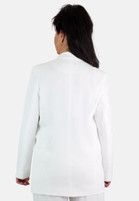 Blazer blanco con corte recto, mangas largas y una textura suave. Presenta sutiles detalles de costura y sin cierres visibles.