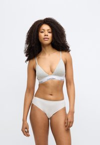 Γκρι σουτιέν σε σχήμα τριγώνου με λεπτές τιράντες και λευκή ταινία με το λογότυπο "Calvin Klein"· συνδυασμένο με ανοιχτό μπεζ ελαστικό σλιπ hipster.