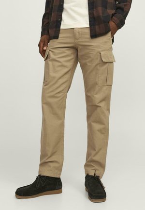 Pantalones cargo beige de algodón, con múltiples bolsillos laterales, corte recto y textura sutil. Combinados con calzado negro.