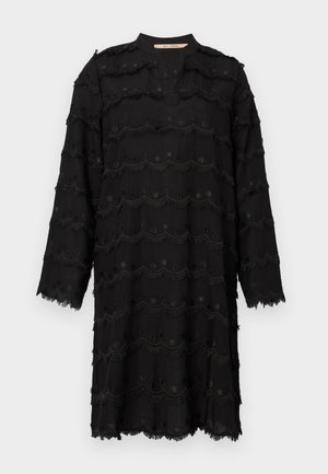 Vestido preto de manga longa com padrões de bordado em franjas e bordas recortadas, decote redondo com uma fenda na frente, e bainha e punhos com acabamento bruto.