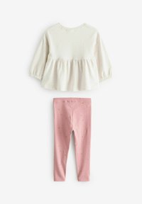 Light beige peplum top with long sleeves and a scoop neckline, paired with pink leggings featuring a gold star pattern.