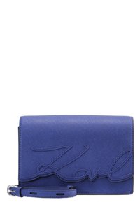 Modrá kožená kabelka s zápěstním popruhem a prošívaným kurzívním nápisem "Karl" na přední straně, texturovaný povrch, obdélníkový tvar, stříbrná spona.