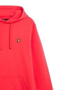 Hoodie corail vif en tissu doux. Il présente une poche frontale et un capuchon ajustable avec un petit logo noir et jaune sur la poitrine.
