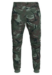 Kamouflagebyxor i bomullsmix, med ett grönt och brunt abstrakt mönster, smal passform, elastiska muddar samt fram- och bakfickor.