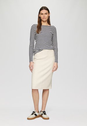 Haut à manches longues rayé bleu marine et blanc associé à une jupe crayon beige clair et des baskets bicolores avec des accents noirs.