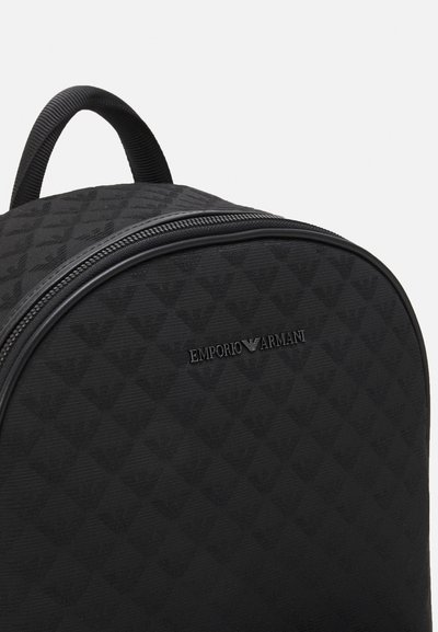Sac à dos noir en tissu texturé avec un motif en losange, doté d'une fermeture éclair et d'un logo en relief sur le devant.