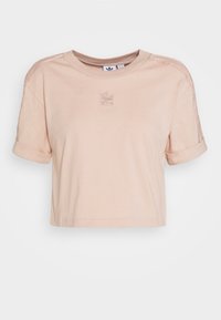 Vaaleanpunainen lyhythihainen crop-top, jossa on käärityt hihat ja pyöreä kaula-aukko. Rinnassa on brodeerattu logo ja pehmeä puuvillakangas.