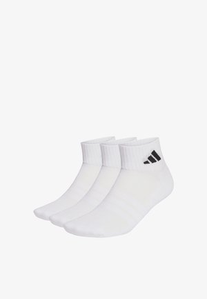 Trzy pary białych skarpetek do kostek wykonanych z miękkiego materiału, z prążkowanymi ściągaczami i czarnymi akcentami z logo. Gładka tekstura z delikatnymi paskami.