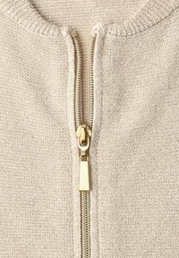 Beiger Strickpullover mit einem goldfarbenen Reißverschluss mit rechteckigem Zuganhänger, strukturierter Stoffqualität und rundem Ausschnitt.