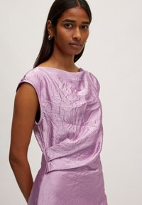 Lilac mouwloos jurkje met een gekreukt textuur en een bootnek. Heeft een losse pasvorm en lichtjes verlaagde armsgaten voor een ontspannen silhouet.