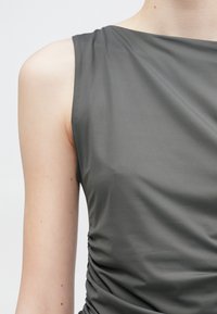 Haut sans manches gris foncé avec une texture lisse et un détail froncé sur le côté. Design simple avec un col bateau et une silhouette minimaliste.