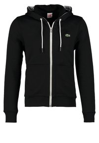 Zwarte rits hoodie gemaakt van een katoenmix, met een grijs gevoerde capuchon, witte trekkoorden, voorzakken en een groen logo op de borst.