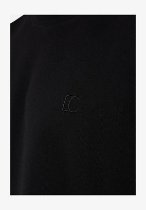 Schwarzer Stoff mit dezent eingesticktem Logo, das ineinander übergehende Buchstaben "E" und "C" in passendem schwarzem Garn auf der Brust zeigt.