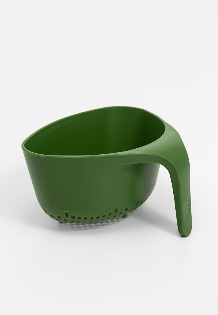 Colador de plástico verde con un mango curvado, forma ovalada, base perforada y textura suave, diseñado para escurrir líquidos de los alimentos.