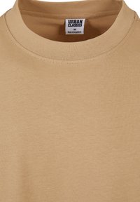Sandfarvet kortærmet t-shirt lavet af blødt bomuld med en ribbet rund hals og et mærke med teksten "URBAN CLASSICS" på den indvendige krave.