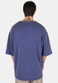 Camicia a maniche corte e di taglio ampio in tessuto blu scuro. Presenta una scollatura ampia e una consistenza sottile. Parte posteriore semplice senza ulteriori decorazioni.