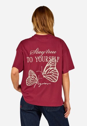 Burgundy short-sleeve T-shirt featuring white text that reads "Stay true TO YOURSELF" above two butterfly graphics.
