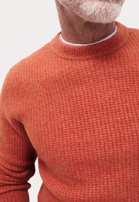 Suéter naranja texturizado con cuello redondo, que presenta un patrón de canalé y una tela suave. Mangas largas y silueta ajustada.