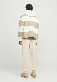 Hooded sweatshirt med vandrette beige og hvide striber; løs pasform. Sammen med beige joggerbukser, der har lomme og tapered manchetter.
