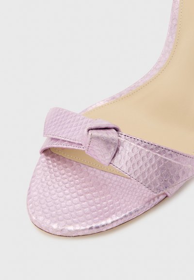 Λιλά υφασμάτινο πέδιλο με ανοιχτά δάχτυλα και ψηλό τακούνι, με μικρό διακοσμητικό φιόγκο στο μπροστινό λουράκι και μπεζ πάτο.