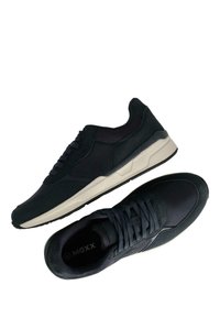 Sneaker nere con un mix di tessuto testurizzato e suede, dotate di una soletta imbottita beige e lacci scuri, progettate per comfort e stile.