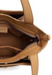 Lysebrun lædertaske med tekstureret overflade, lynlåslukning og to håndtag. Indvendigt har den flere rum og en brun foer.