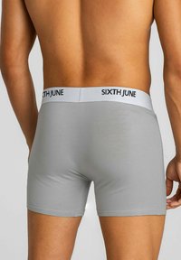 Szare bokserki o dopasowanym kroju, wykonane z gładkiego materiału, z białym pasem w talii oznaczonym napisem "SIXTH JUNE".