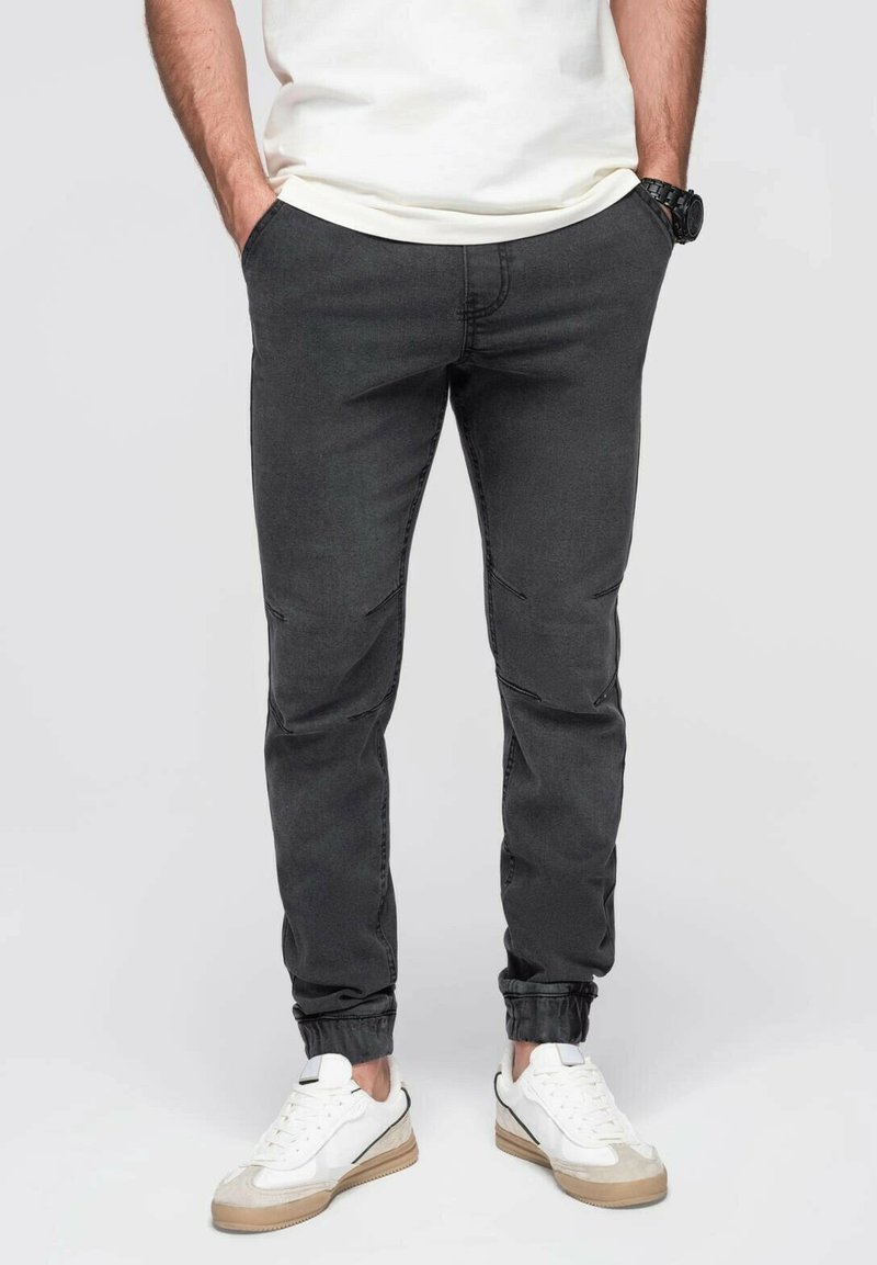 Pantalones jogger gris oscuro con cintura elástica y tobillos ajustados, con una textura suave y detalles de costura sutiles.