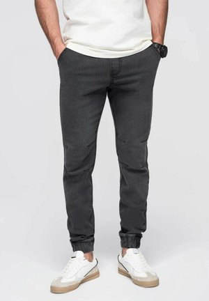 Pantalones jogger gris oscuro con cintura elástica y tobillos ajustados, con una textura suave y detalles de costura sutiles.