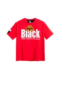 Camiseta de algodón roja con texto blanco que dice "Black" y un gráfico de un perro marrón encima. Mangas cortas y etiqueta con la inscripción "MOD WAVE MOVEMENT".