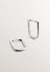 Dos pendientes de aro rectangulares de plata pulida con bordes redondeados sobre una superficie clara y lisa.