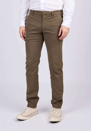 Chinos kaki à coupe droite, fabriqués en tissu coton doux. Équipés de passants de ceinture et de poches avant, associés à des baskets blanches.