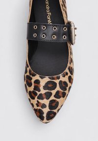 Chaussure plate à imprimé léopard avec un bout pointu et une sangle en cuir noir ornée d'œillets en métal et d'une boucle métallique.