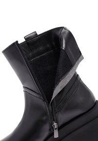 Czarne skórzane botki za kostkę z zamkiem błyskawicznym, z miękkim, teksturowanym wnętrzem i kontrastowym szarym mankietem. Podwyższona podeszwa dla lepszej stabilności.