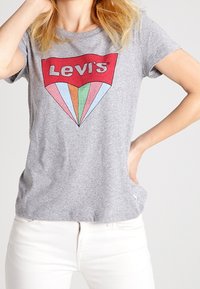 T-shirt in cotone grigio con logo rosso "Levi's" e grafica a diamante con colori pastello. Maniche corte e vestibilità rilassata.
