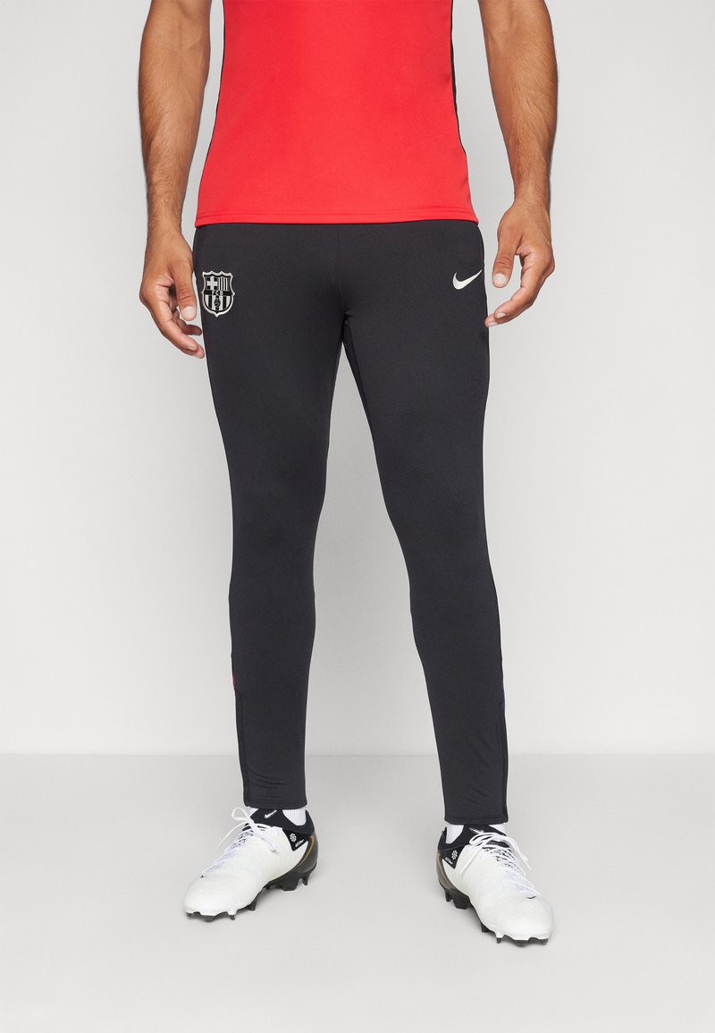 Czarne sportowe spodnie o dopasowanym kroju, z logo Barcelony na lewej udzie i znakiem Nike na prawej biodrze.