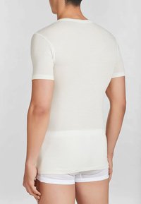 T-shirt fitted a maniche corte in tessuto crema chiaro. Presenta un girocollo e una texture liscia, adatto per sovrapposizioni o per un look casual.