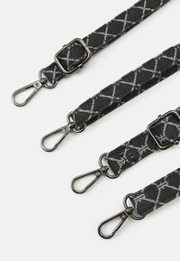 Quatre sangles en tissu réglables noires et grises avec des motifs croisés blancs et des boucles pivotantes en métal sur fond blanc.