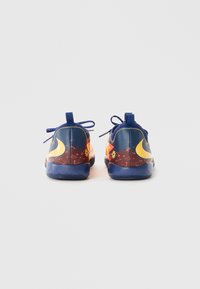 Nike sporta apavi ir ar gradienta dizainu tumši zilos un oranžos toņos, ar gludu tekstūru un kontrastējošiem dzelteniem logotipa akcentiem.