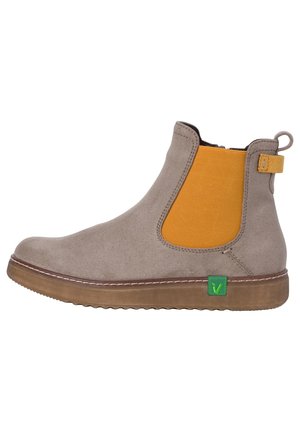Bottine en daim taupe avec panneau latéral élastique moutarde, semelle en caoutchouc marron et étiquette verte sur le côté extérieur.