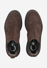 Chaussures en suède marron à enfiler avec une semelle en caoutchouc noir texturé. Bout arrondi et panneaux élastiques sur les côtés pour un enfilage facile. Logo visible sur la semelle intérieure.