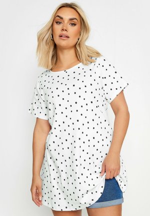 T-shirt blanc à manches courtes avec un motif d'étoiles noires, col rond et coupe à la longueur des hanches avec ourlet arrondi.